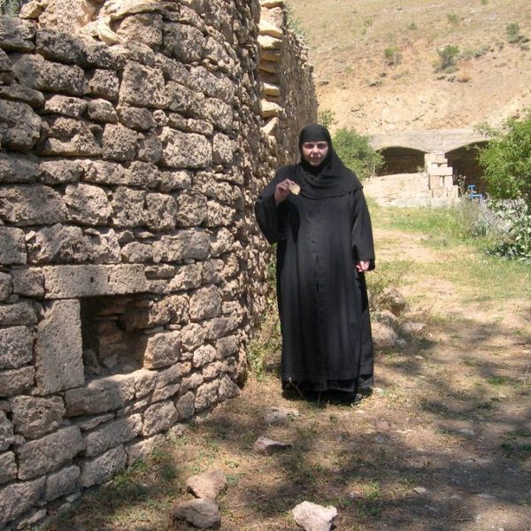 Η Ηγουμένη Μαριάμ στην εξωτερική περίφραξη των κελίων της Μονής, όπου κρατάει τεμάχιο πέτρας το οποίο μετέφερε πίσω στην Ελλάδα και φυλάσσεται στην Ιερά Μονή Αγίας Παρασκευής.
